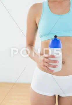 Fit woman holding water bottle at fitness studio Stock Photos