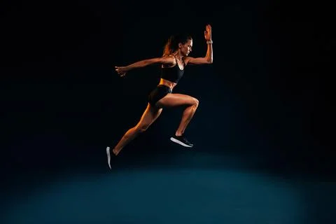 Fit woman running and jumping in the studio. Young female sprinting Stock Photos