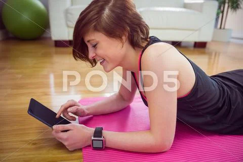 Fit woman using tablet pc on mat Stock Photos
