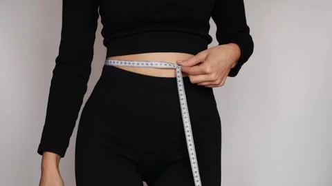 Fit woman in workout clothes checking waist size with tape. Stock Footage 306280765
