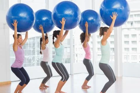 Fit women holding blue fitness balls in exercise room Stock Photos