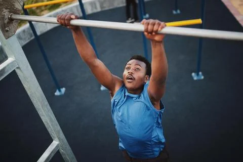 Fit young black man doing pull ups at an outdoor gym Stock Photos