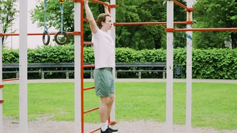 Fit young man doing a hanging core and abs workout at an outdoor gym. He perform Stock Footage 342811147