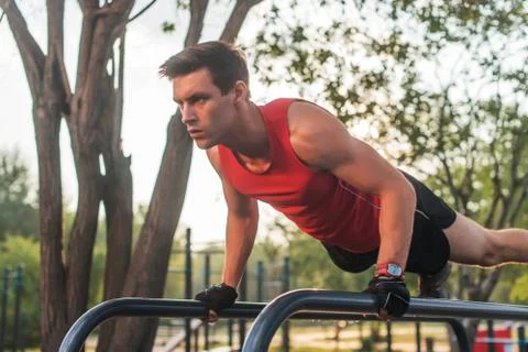 Fit young man doing push ups on horizontal bar outdoors 스톡 사진