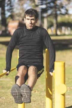 Fit young man doing push ups on horizontal bar outdoors Stock-Fotos