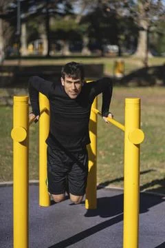 Fit young man doing push ups on horizontal bar outdoors Stock-Fotos