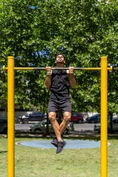 Fit young man executing pull-ups in a park setting Stock Photos