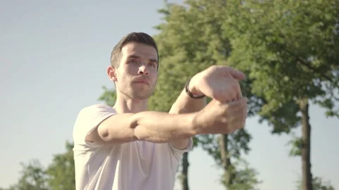 Fit young man preparing for workout doing stretching exercise for arms Stock Footage 146307172