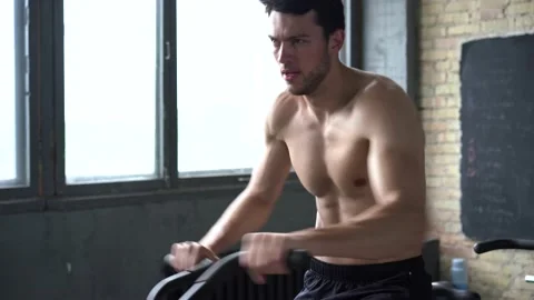 Fit young man using exercise bike at the gym Stock Footage 131218162