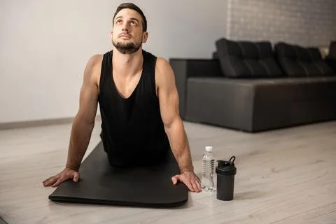 Fitn man meditating while doing cobra pose in living room. Indoor shot of Stock Photos