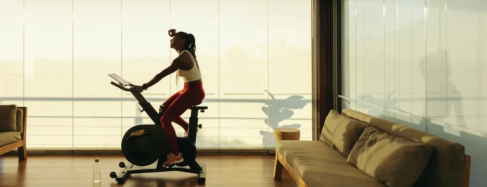 Fitness and wellbeing: African woman using exercise bike for healthy lifestyl Stock Photos