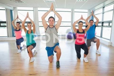Fitness class and instructor kneeling in Namaste position Stock Photos