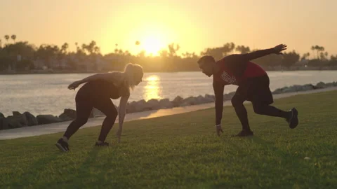 Fitness coach and client do crossover exercise routine- golden hour Marina park Stock Footage 136035599