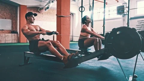 Fitness couple training on row ergometer machine at cross gym Stock Footage 79392602