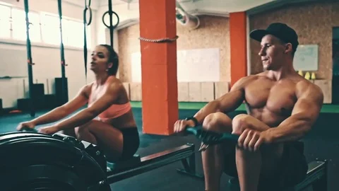 Fitness couple training on row ergometer machine at cross gym Stock Footage 79393555
