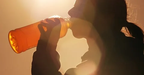 Fitness girl drinking sports drink from plastic bottle outside in park Stock Footage