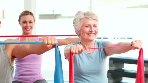 Fitness group sitting on exercise balls stretching resistance bands Video stock 34133645