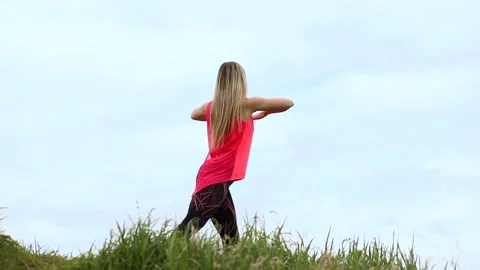 Fitness instructor is doing exercises outdoors in the park. Blue sky background. Stock Footage 131312181