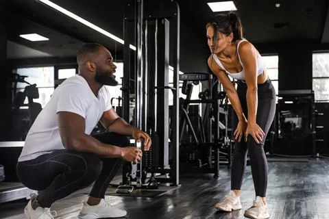 Fitness instructor exercising with his client at the gym, african man and cau Foto stock