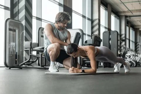 Fitness instructor exercising with his client at the gym. Stock Photos
