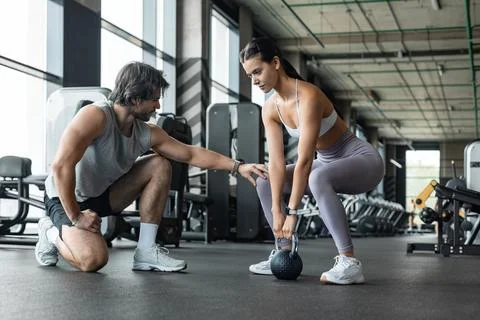 Fitness instructor exercising with his client at the gym. Stock Photos