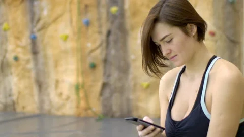 Fitness lady is using phone while sitting in sports club. Video stock 85623826