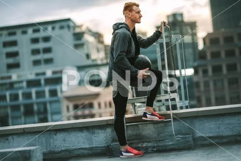 Fitness man standing on rooftop holding a medicine ball Stock Photos