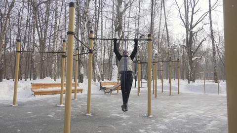 Fitness man training pull up exercise on sport ground. Outdoor winter training Video stock 88175343