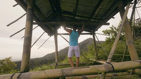 Fitness man training pulling up exercise on horizontal bar in tropical forest Stock Footage 107137022