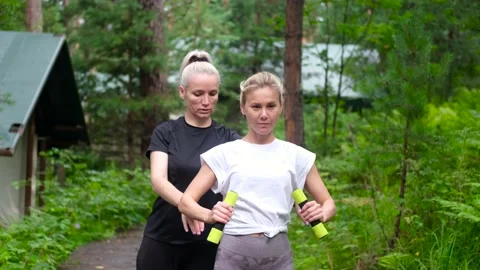 Fitness. Personal trainer taking notes while woman exercising outdoors. Two Stock Footage 234098309