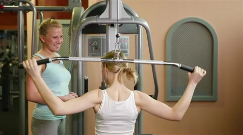 Fitness trainer explaining lat machine in gym Stock Footage 10559961