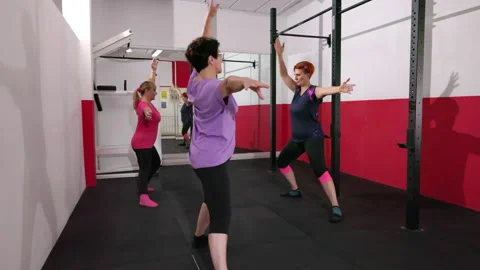 Fitness trainer trains two aged women at gym Stock Footage 227367146