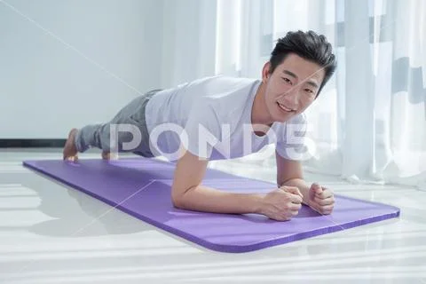 Fitness training athletic sporty man doing plank exercise in gym or yoga clas Stock Photos