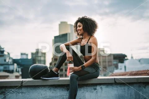 Fitness woman sitting on rooftop taking break from workout Stock Photos
