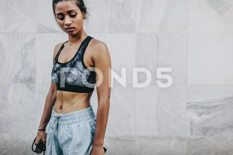 Fitness woman standing outdoors holding skipping rope Stock Photos