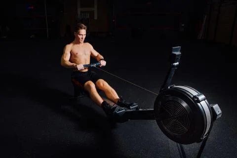 Fitness young man using rowing machine in the gym Stock Photos
