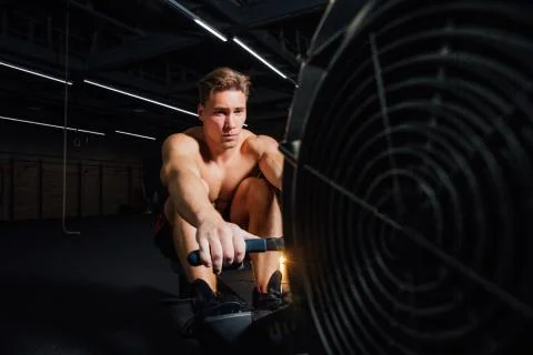 Fitness young man using rowing machine in the gym Stock Photos