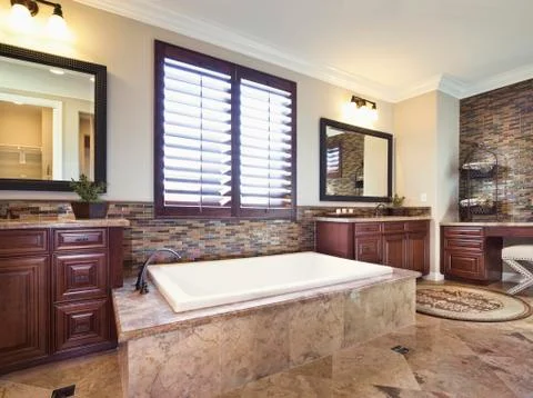 Fitted bathtub below shutter window Stock Photos