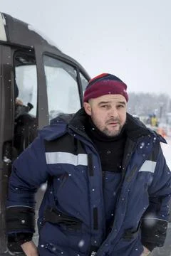 A fitter in a blue jacket gets out of the cab of a car Fotos Stock