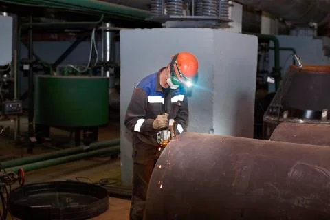 Fitter processes pipe edge with electric hand grinder Stock Photos