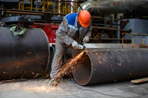 Fitter processes pipe edge with electric hand grinder Stock Photos