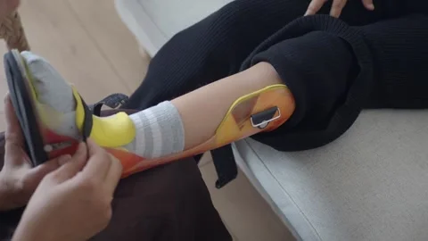 Fitting a foot brace for ankle support in a living room Stock Footage 330148798