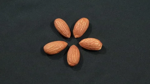 Five Almonds Arranged In Star Shape Rotating On Black 4K Video stock 332843903