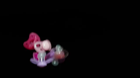 Five baby pacifiers fly up against a black background Stock-Footage 148337231