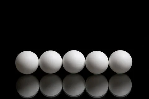 Five balls for ping pong in a row on a dark background Foto stock