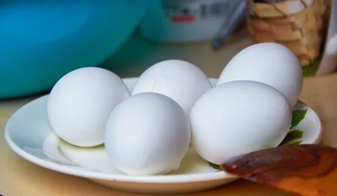 Five boiled eggs in a shell on a plate. One egg with cracks in a scarlet shel Stock Photos