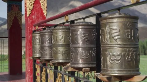 Five buddhist prayer wheels spin against a mountain backdrop in Ladakh Video stock 309330664