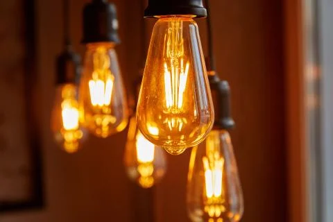 Five burning bulbs hang randomly, close-up, on a blurred background Stock Photos