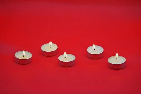 Five burning small round candles on a bright red background 스톡 사진