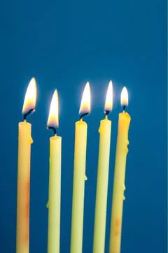 Five burning thin candles on a blue background Stock Photos
